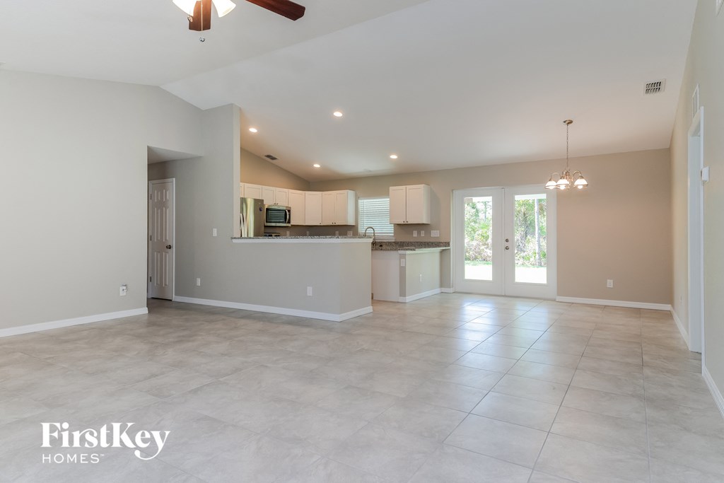 an empty living room and kitchen with a door to the patio