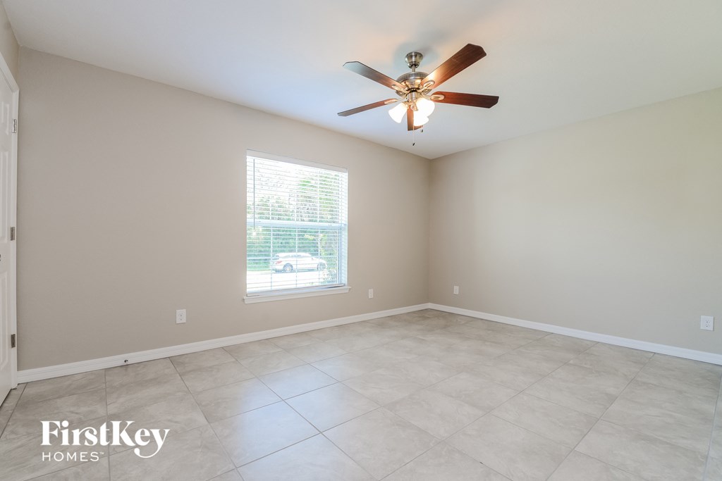 an empty living room with a ceiling fan and a window