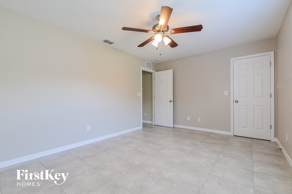 the spacious living room with ceiling fan and tile flooring