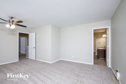 a living room with white carpet and a ceiling fan