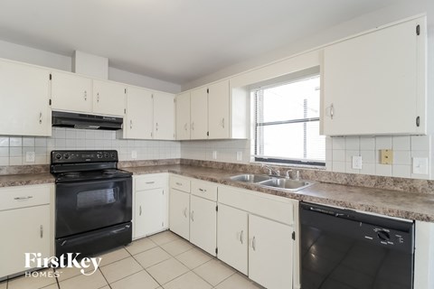 a kitchen with white cabinets and black appliances