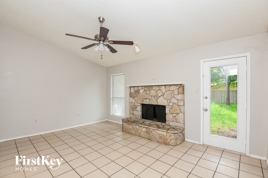 a living room with a stone fireplace and a ceiling fan