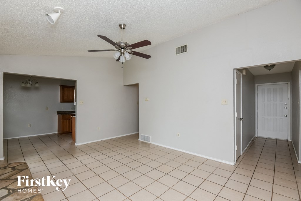 an empty living room with a ceiling fan and a tiled floor