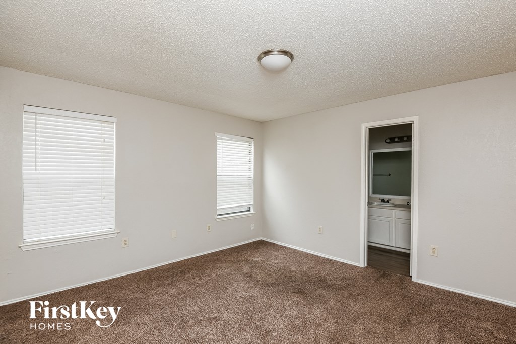an empty living room with carpet and a door to a bathroom