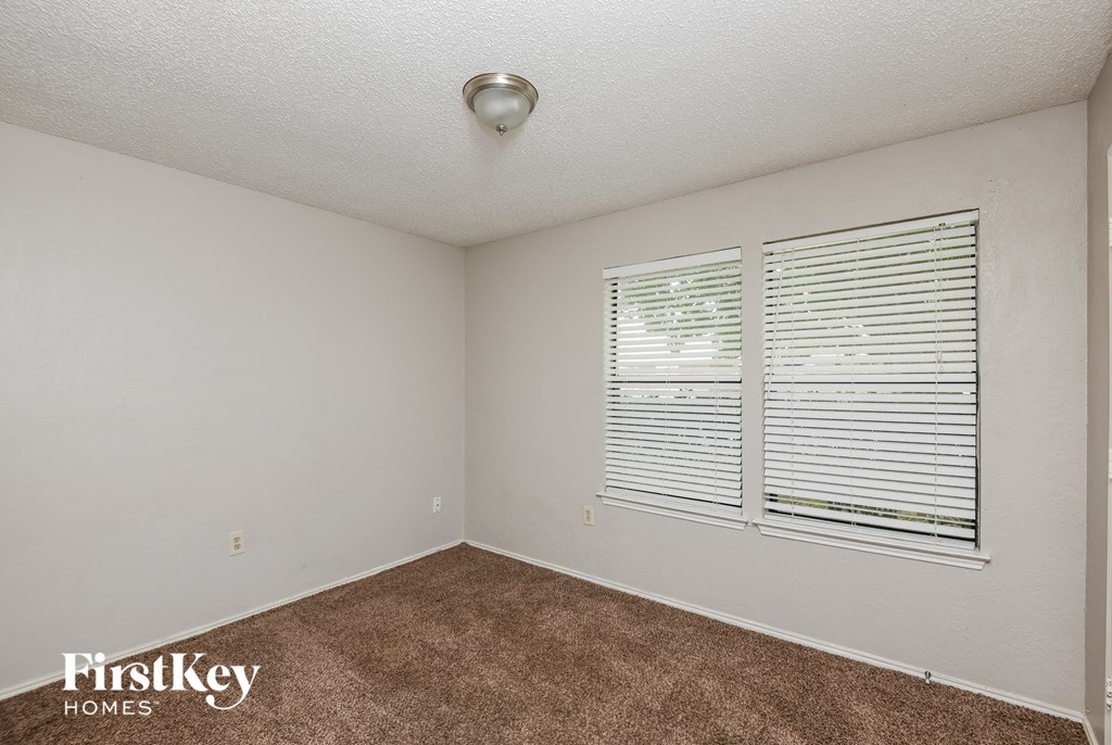 the living room of an apartment with a carpeted floor and two windows