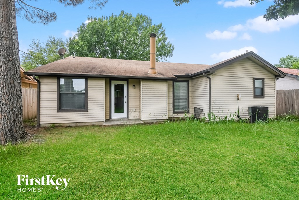 the front of a white house with a yard and a tree