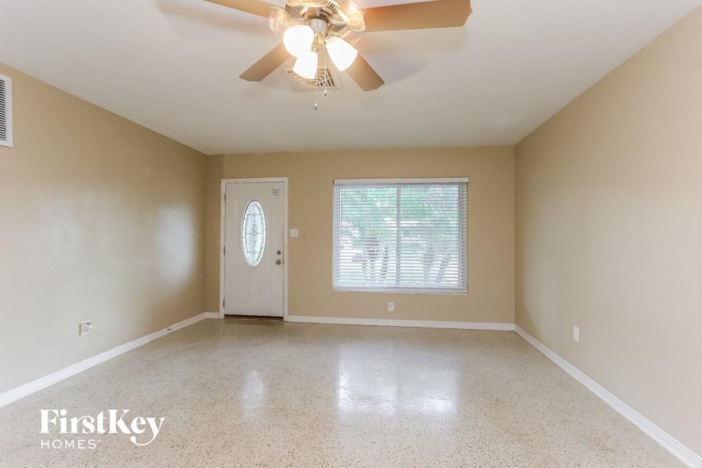 A spacious room with a ceiling fan and a door.