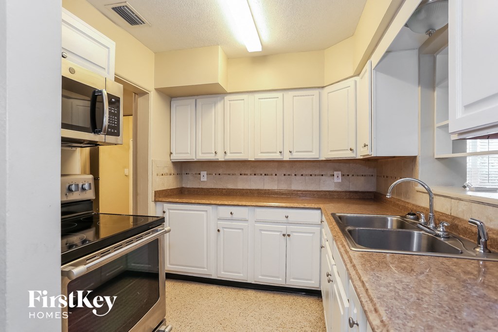 A kitchen with white cabinets and a black countertop.