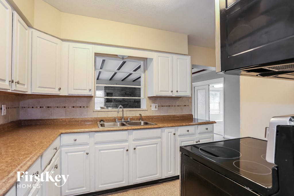 A kitchen with white cabinets and a black stove top oven.
