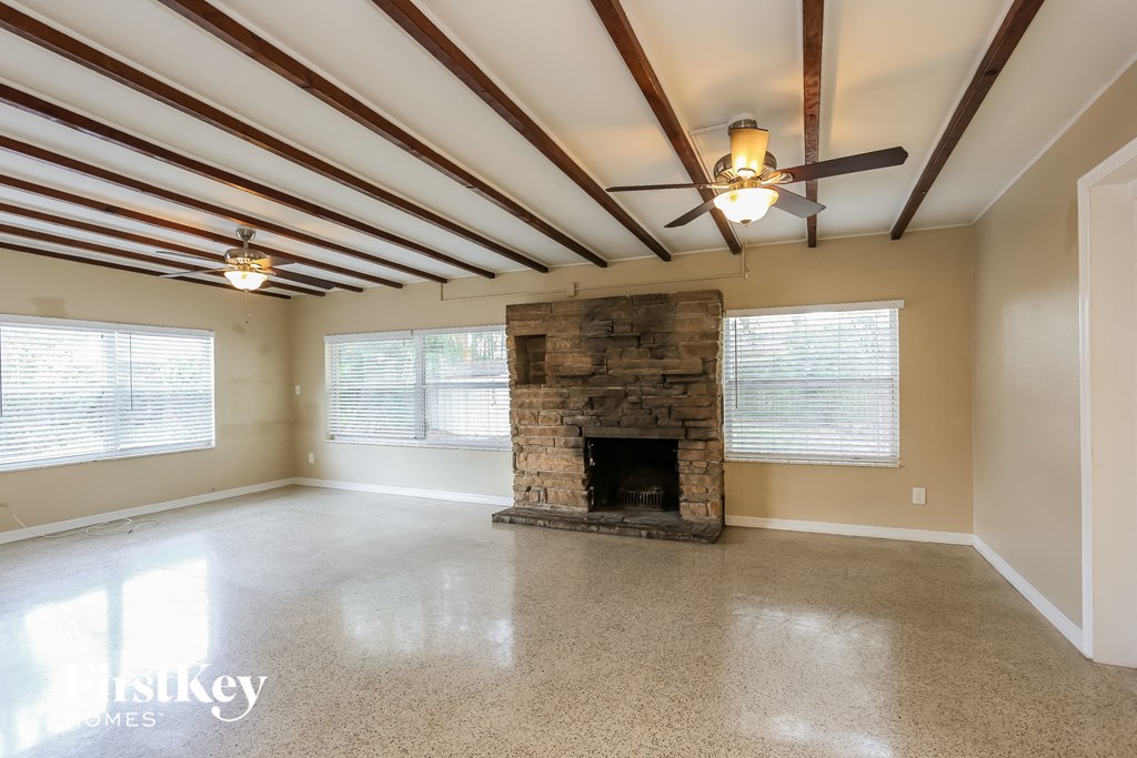 A spacious room with a fireplace and a ceiling fan.