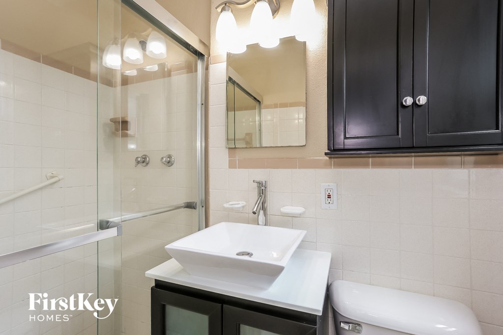 A bathroom with a white sink and black cabinets.
