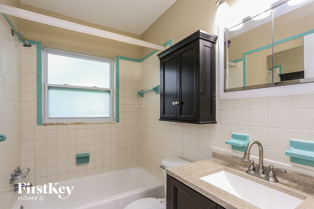 A bathroom with a tub, sink and mirror.