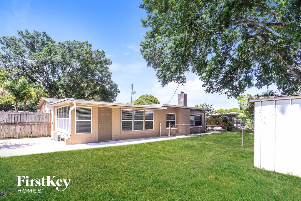 A house with a fence and trees in the background.