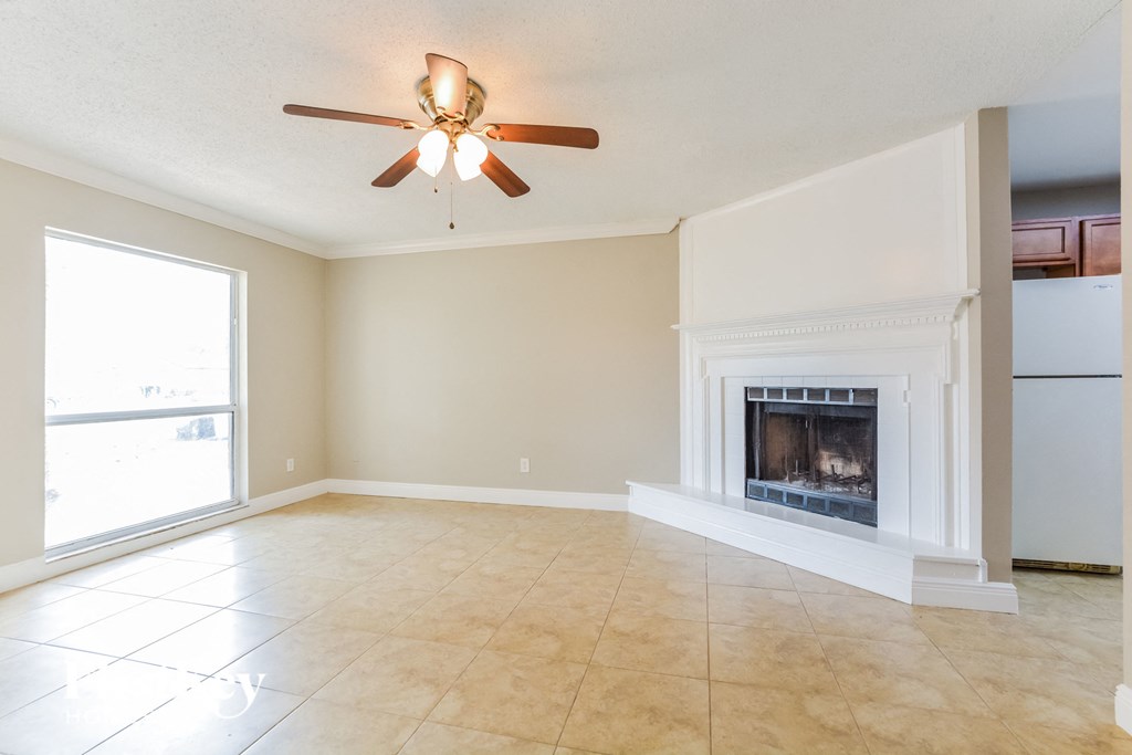 an empty living room with a fireplace and a ceiling fan