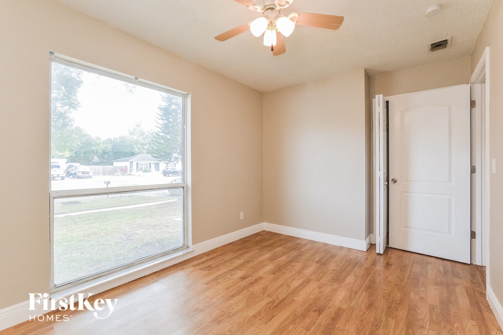an empty living room with a large window and a ceiling fan