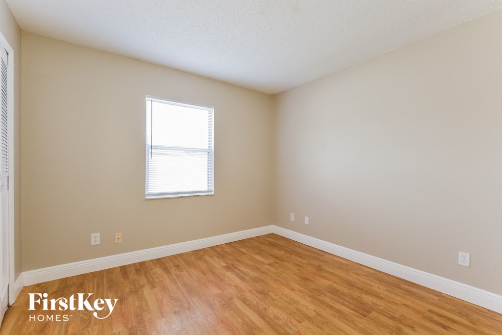 a bedroom with wood floors and a window