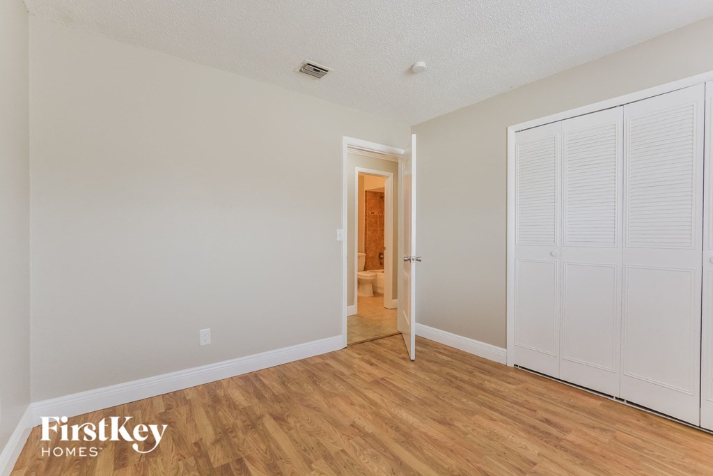the living room of an apartment with wood flooring and white doors