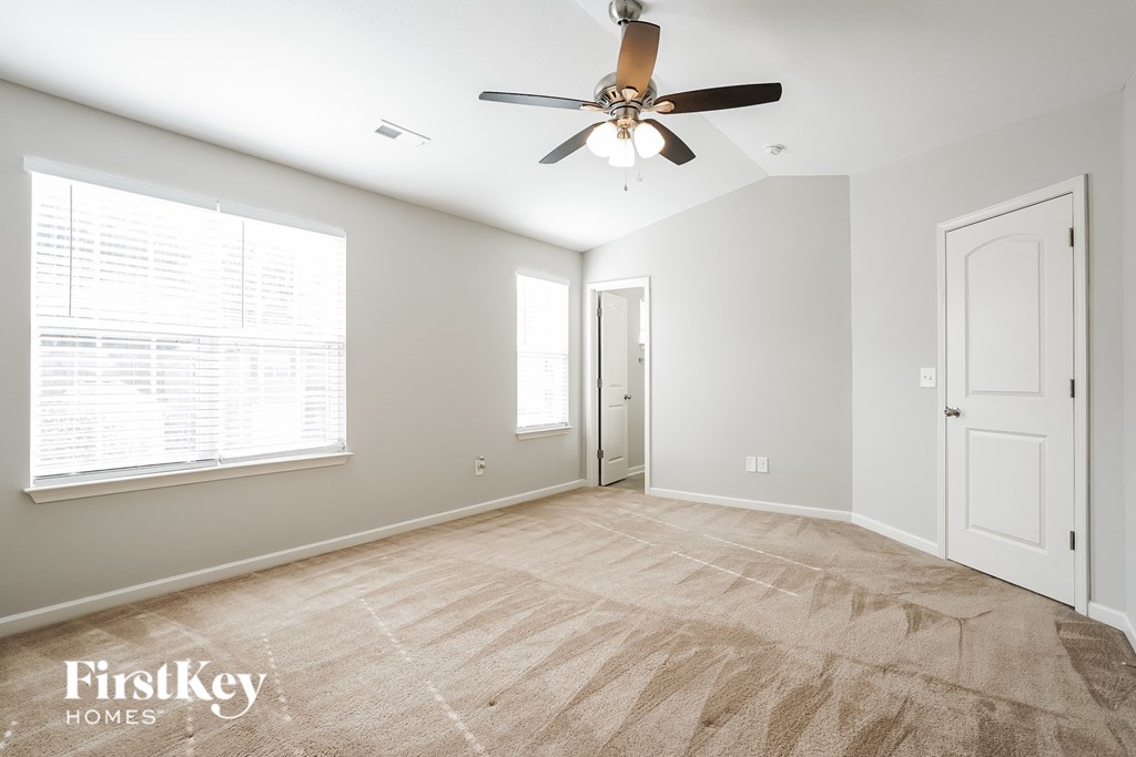 A spacious room with a carpeted floor and a ceiling fan.