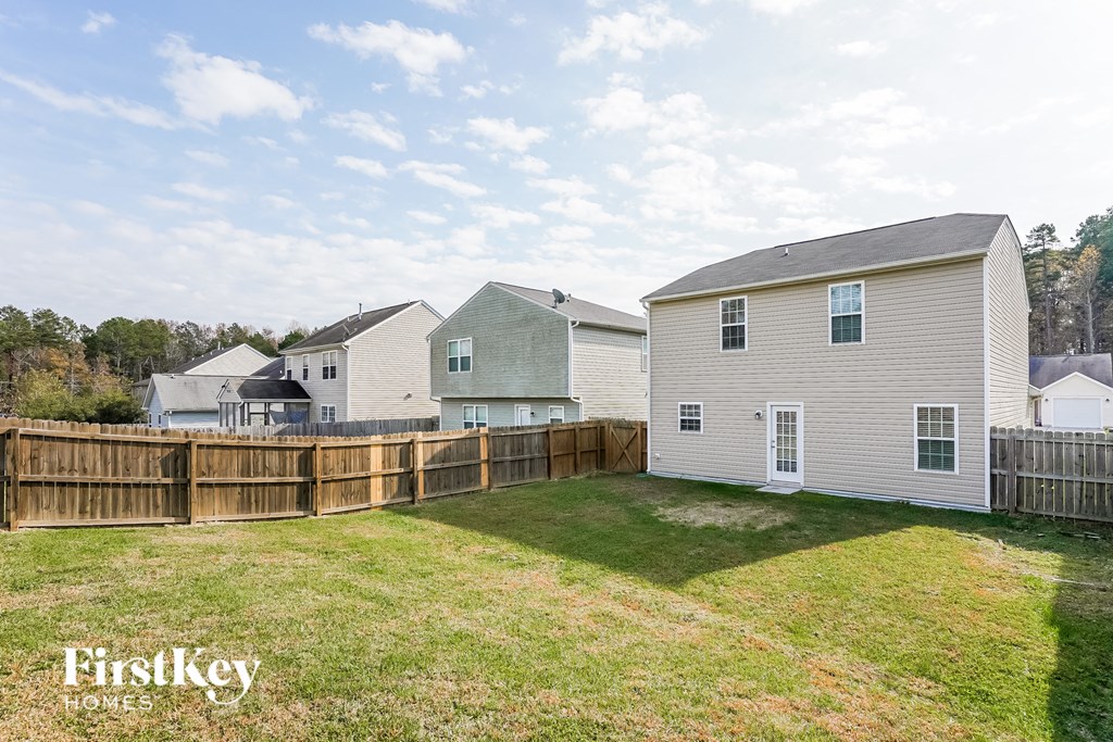 A grassy yard with a fence and two houses with the words "FirstKey Homes" on the bottom.