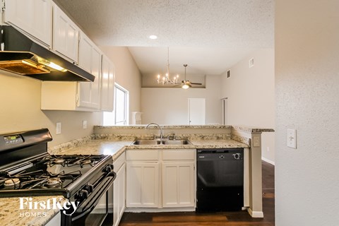 A kitchen with a black stove top oven and white cabinets.
