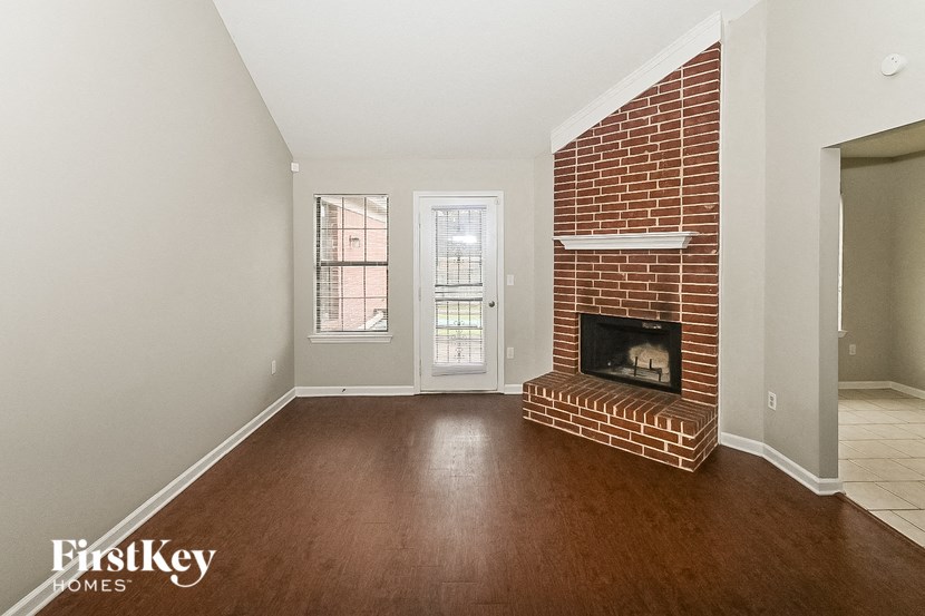 a living room with a brick fireplace and wooden floors
