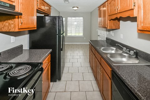 a kitchen with wood cabinets and black appliances and tiled flooring