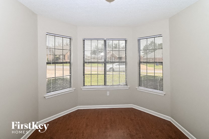 a living room with three windows and a wooden floor