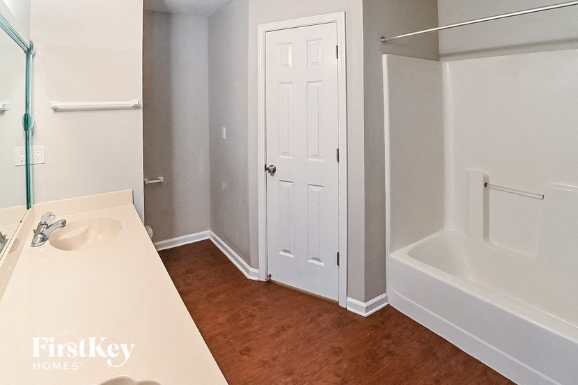 a bathroom with a white door and a sink and a bath tub