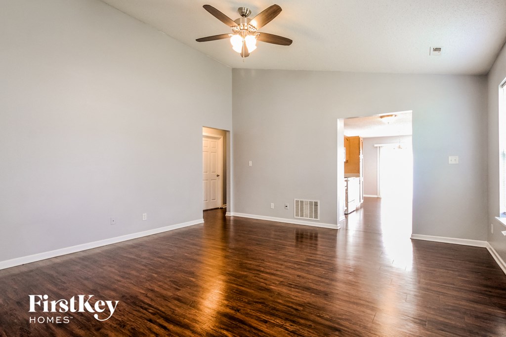 A spacious room with a ceiling fan and wooden flooring.