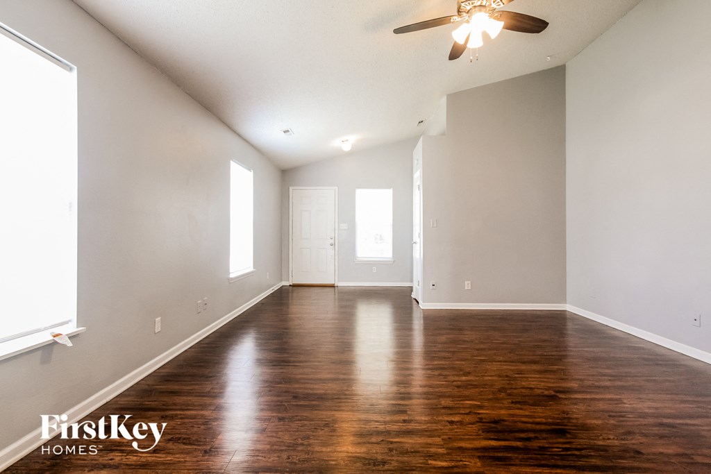 A spacious room with wooden floors and a ceiling fan.