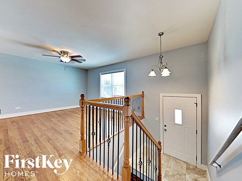an upstairs landing with a door to the hallway and a ceiling fan