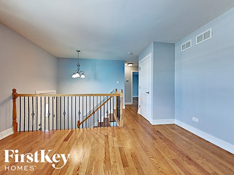 the upstairs landing of a house with a staircase and blue walls and wood floors