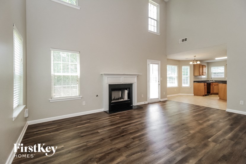 an empty living room with a fireplace and a kitchen
