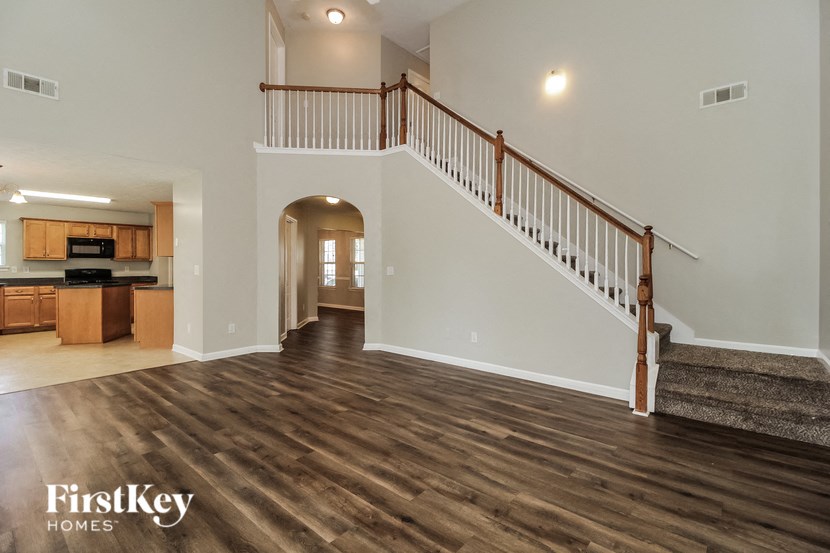 a living room with a staircase and a kitchen in a house