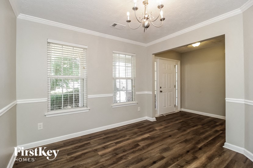an empty living room with a door and a chandelier