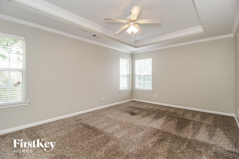 an empty living room with a ceiling fan and window