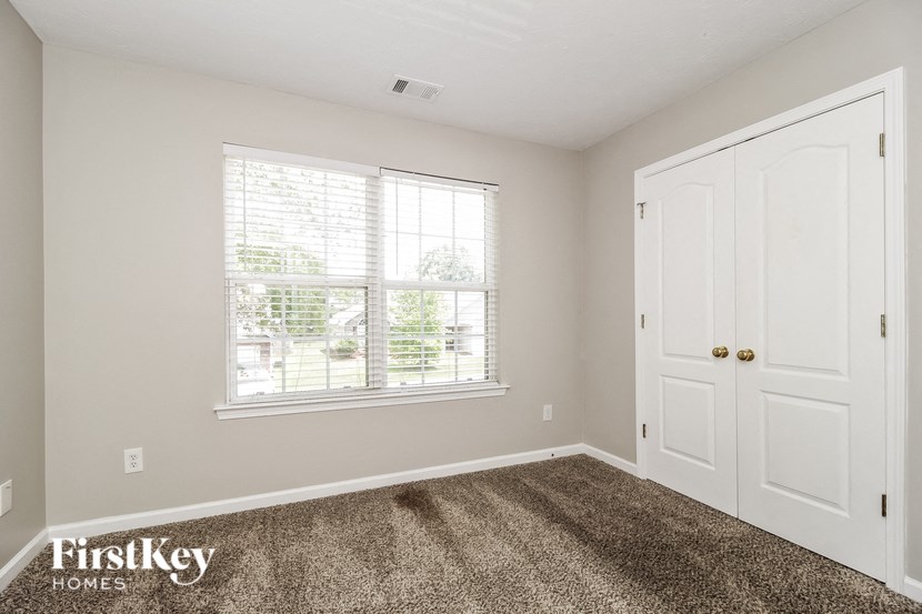 the bedroom of a home with a carpeted floor and a window