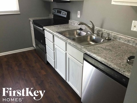 A kitchen with a stainless steel dishwasher and a granite countertop.