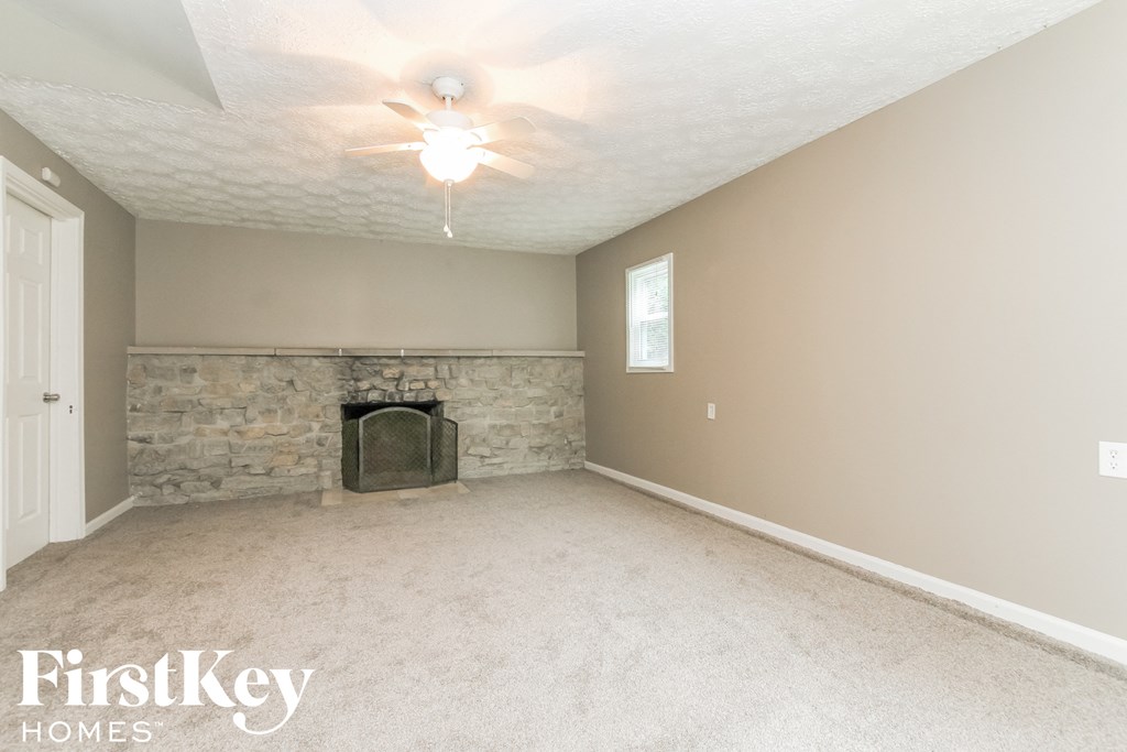 a living room with a stone fireplace and a ceiling fan