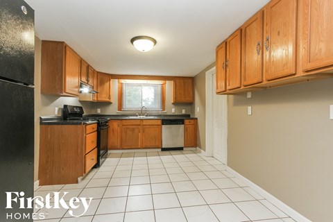 a kitchen with wooden cabinets and a white tiled floor and a window
