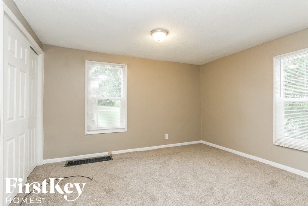 a bedroom with a carpeted floor and two windows