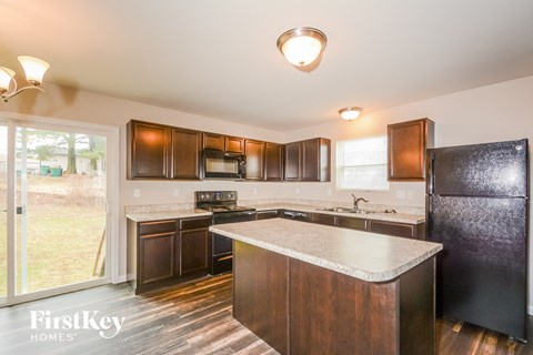 a kitchen with dark wood cabinets and white counter tops and a black refrigerator