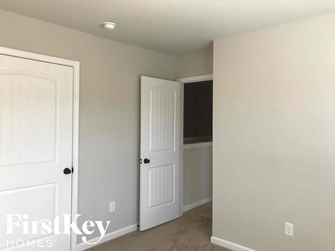 a bedroom with a closet and a white door and a mirror