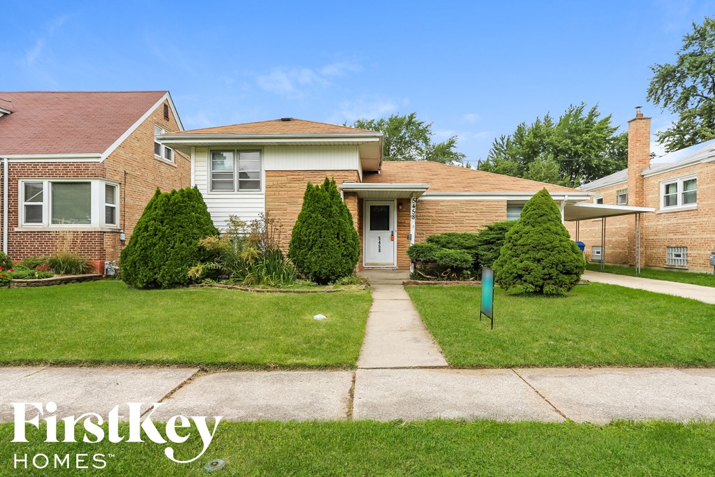 a small brick house with a lawn and sidewalk in front of it