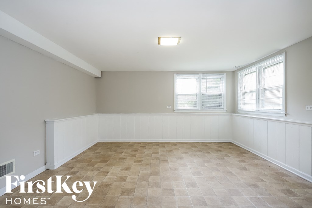 an empty living room with two windows and a tiled floor