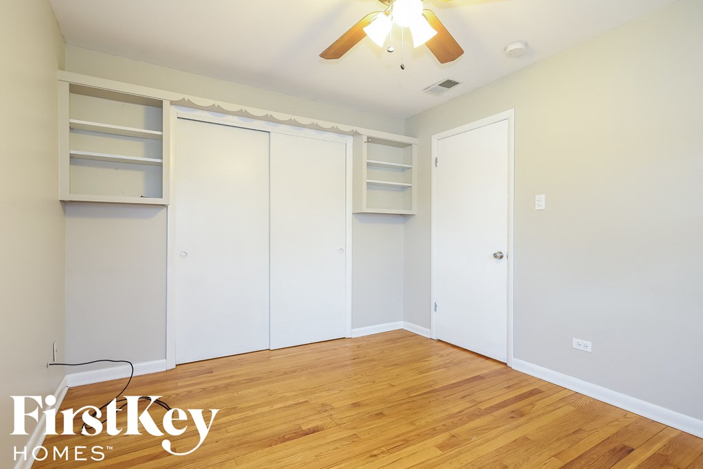 a bedroom with white closets and a wooden floor and a ceiling fan