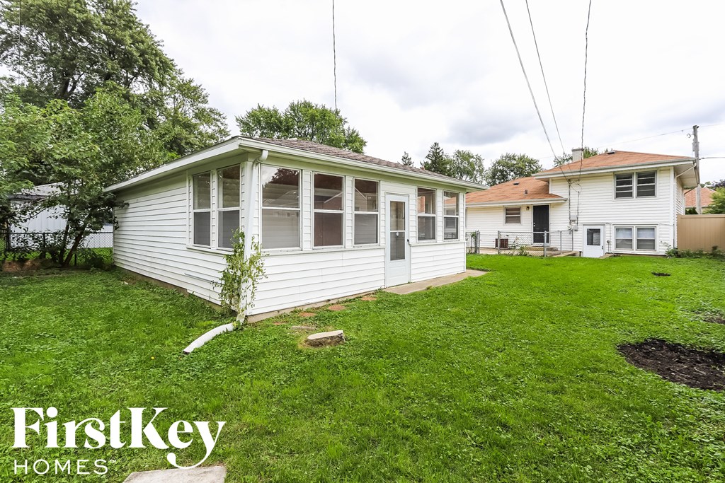a backyard with a white house and a yard with green grass