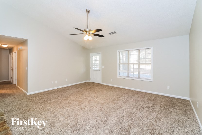 a spacious living room with carpet and a ceiling fan