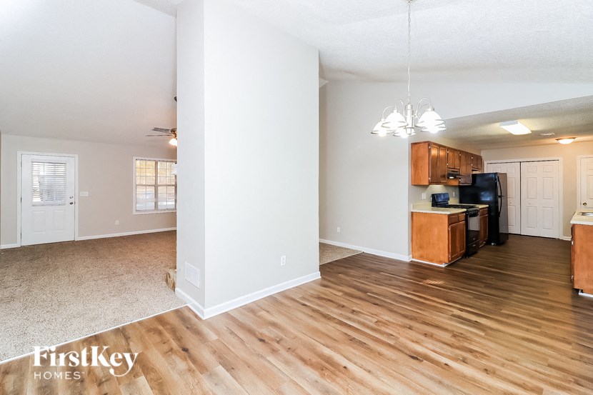 a living room and kitchen with wood floors and white walls