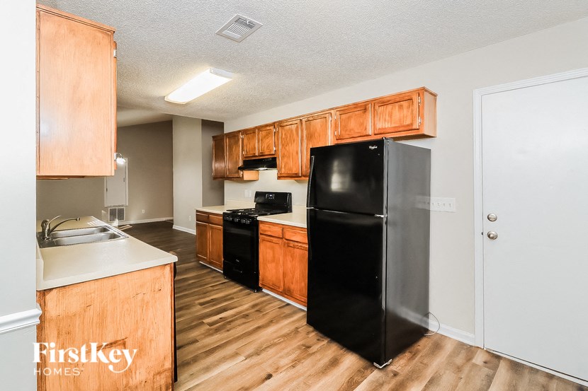 a kitchen with wooden cabinets and a black refrigerator